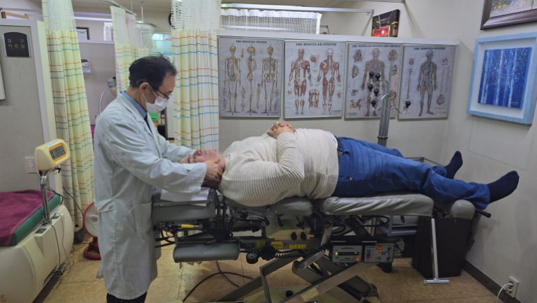 الدكتور سو-يوم يمارس العلاج الطبيعي على عنق موفد الجزيرة نت