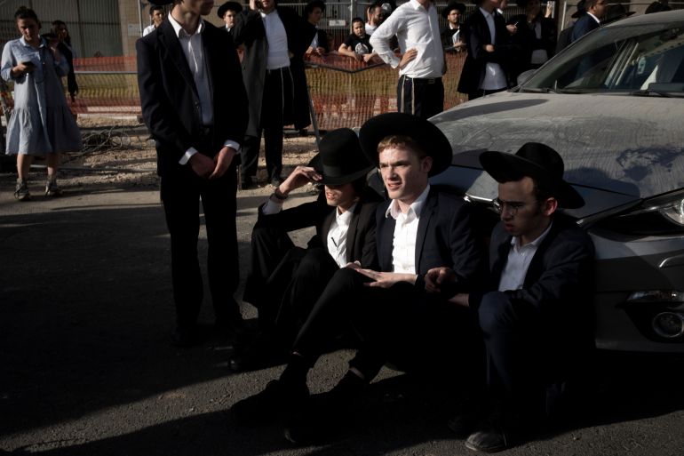 Ultra-Orthodox Jewish men block a car from crossing Jaffa Street in central Jerusalem, Thursday, Sept. 29, 2022 to protest attempts to force them to register for Israel's military draft. Military service is mandatory for most Jewish Israeli men, but the ultra-Orthodox often receive exemptions in order to continue their religious studies. (AP Photo/ Maya Alleruzzo)