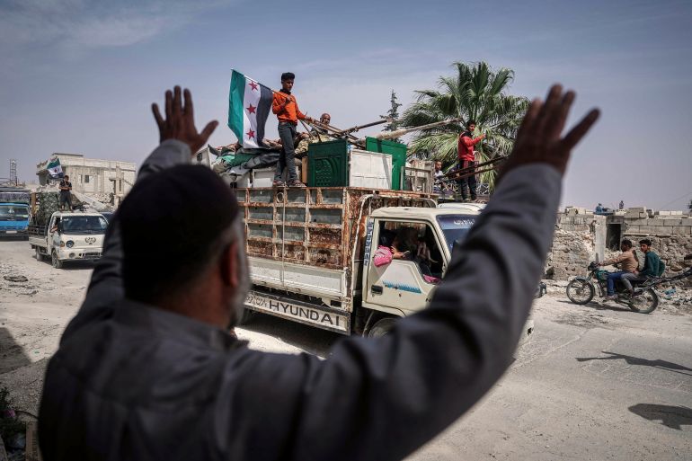 A man greets trucks carrying displaced families as they return, supported by an NGO, to their village after more than five years in the Atmeh camps near the Syrian-Turkish border, in Kafr Sijna, south of Idlib, Syria, Sunday, May 18, 2025. (AP Photo/Ghaith Alsayed)