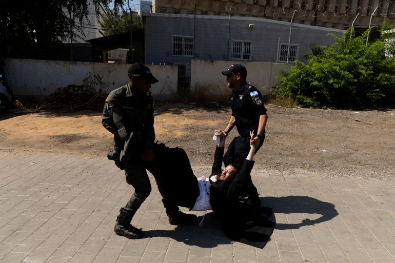 RAMAT GAN, ISRAEL - AUGUST 5: Police officers disperse an an Ultra Orthodox Jewish protester during a demonstration against drafting to the Israeli military near a recruitment base on August 5, 2024 in the Tel HaShomer area of Ramat Gan, Israel. Hundreds of Ultra-Orthodox men who were previously exempted from military service were due to arrive at the recruitment office here today, following a Supreme Court ruling that ended the exemption for yeshiva students. (Photo by Amir Levy/Getty Images)