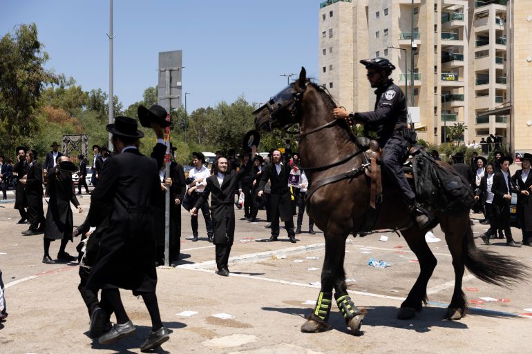 RAMAT GAN, ISRAEL - AUGUST 5: Ultra-Orthodox Jewish men clash with mounted police officers during a demonstration against drafting to the Israeli military near a recruitment base on August 5, 2024 in the Tel HaShomer area of Ramat Gan, Israel. Hundreds of Ultra-Orthodox men who were previously exempted from military service were due to arrive at the recruitment office here today, following a Supreme Court ruling that ended the exemption for yeshiva students. (Photo by Amir Levy/Getty Images)