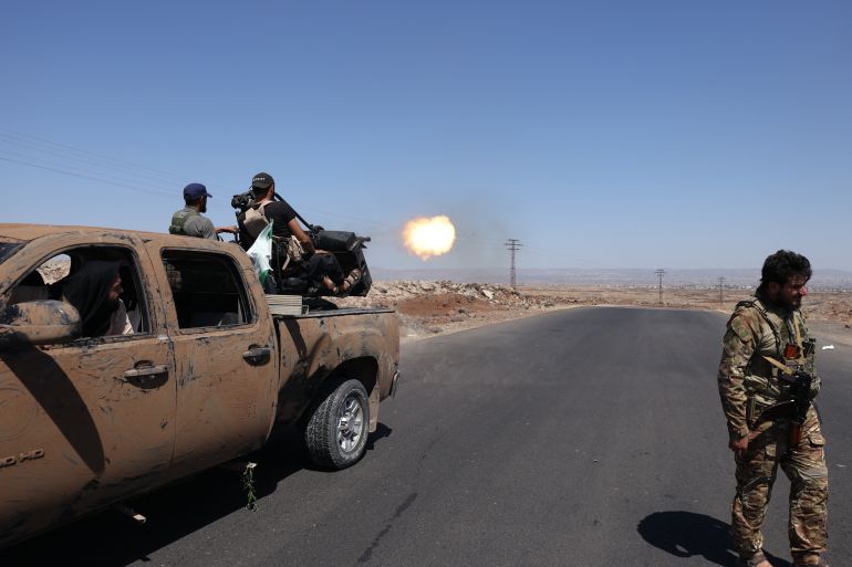TOPSHOT - Syrian security forces fire towards a position near the Mazraa area, near Sweida on July 14, 2025, following clashes between Bedouin tribes and local fighters in the predominantly Druze city.