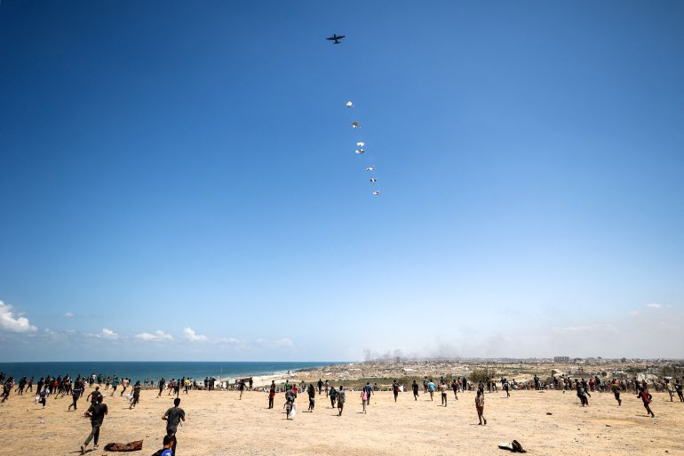 TOPSHOT - People rush to the scene as a German Air Force (Luftwaffe) military transport aircraft airdrops humanitarian aid pallets over Nuseirat in the central Gaza Strip during a relief mission above the Israel-besieged Palestinian territory on August 5, 2025.