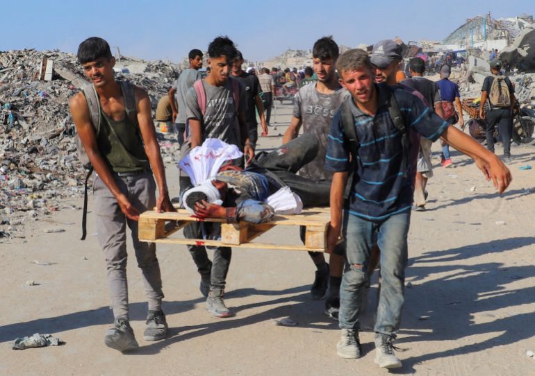 SENSITIVE MATERIAL. THIS IMAGE MAY OFFEND OR DISTURB Palestinians carry a person wounded by Israeli fire, on a pallet, after aid supplies that entered Gaza through Israel arrived, in Beit Lahia, northern Gaza Strip, August 3, 2025. REUTERS/Ebrahim Hajjaj TPX IMAGES OF THE DAY