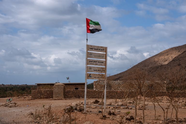 SOCOTRA ISLAND, YEMEN - OCTOBER 12: A United Arab Emirates flag flies over a sign for the Abu Dhabi Fund for Development in a small village on October 12, 2025 in Socotra, Yemen. Socotra, the largest island in an eponymous archipelago, lies 150 miles off the Horn of Africa, and even farther from mainland Yemen. Its relative isolation has mitigated the impact of Yemen's long-running and stalemated civil war, rendering it safe enough to attract a small but steady stream of foreign tourists. However, it has not been untouched by regional hostilities. In recent years, the UAE-backed secessionist group Southern Transitional Council wrested control of the island from the Saudi-backed internationally recognized government. The STC ultimately joined the government's Presidential Leadership Council, but the UAE retains considerable military and economic influence in the archipelago. (Photo by Carl Court/Getty Images)