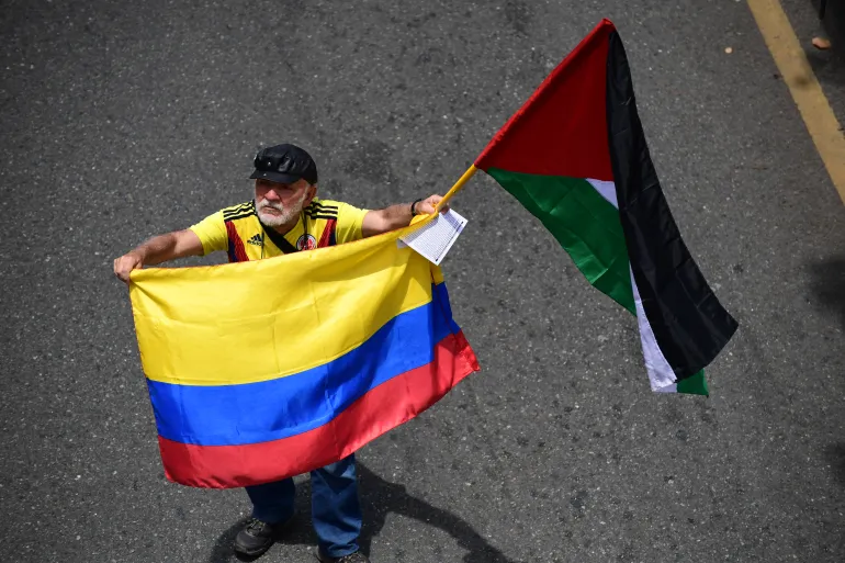 A demonstrator holds a Colombian and Palestinian flags during a May Day rally marking International Workers Day, in Medellin, Antioquia department, Colombia, on May 1, 2026. (Photo by Jaime SALDARRIAGA / AFP)